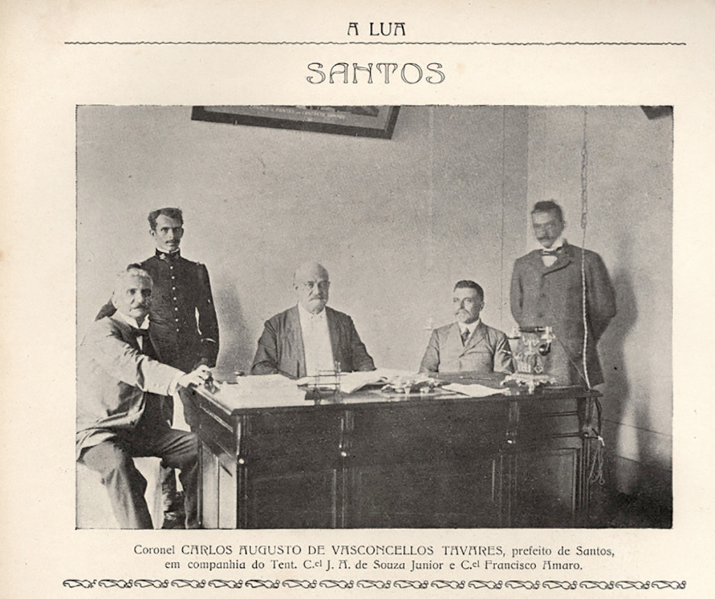 Imagem do então prefeito de Santos, o primeiro da história, coronel Carlos Augusto de Vasconcelos Tavares, em sua mesa de trabalho, ao lado de alguns auxiliares.